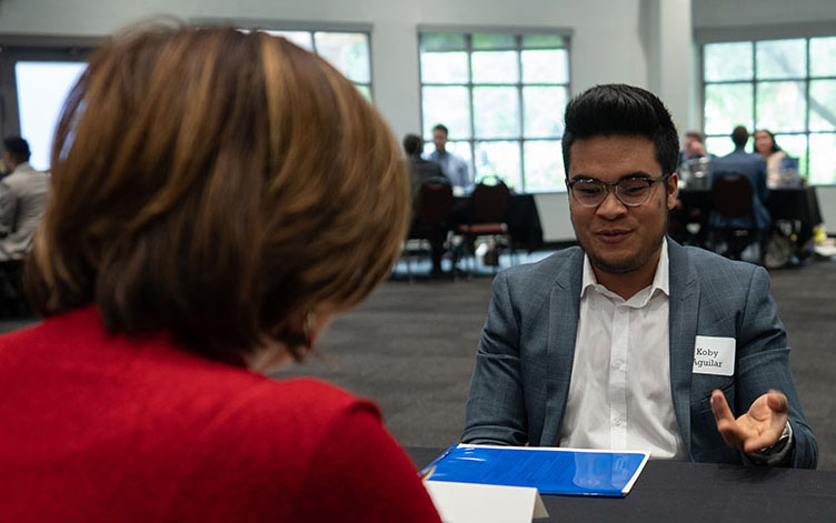 Student sitting at a table speaking with community member.